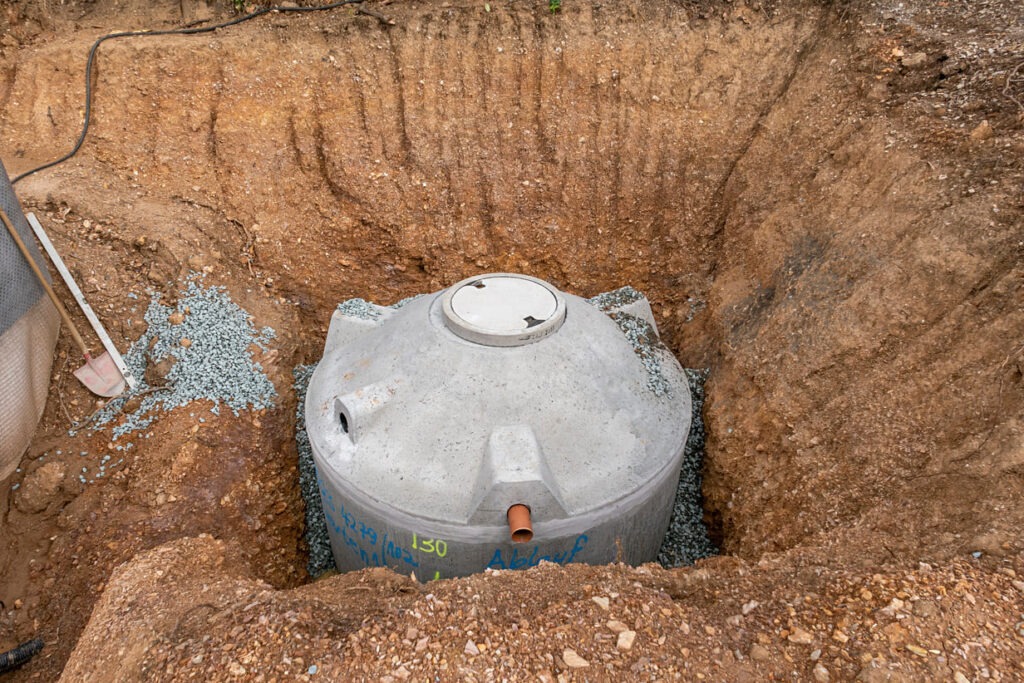 Eine teilweise vergrabene Zisterne, die für die Speicherung von Regenwasser zur Gartenbewässerung vorbereitet wird