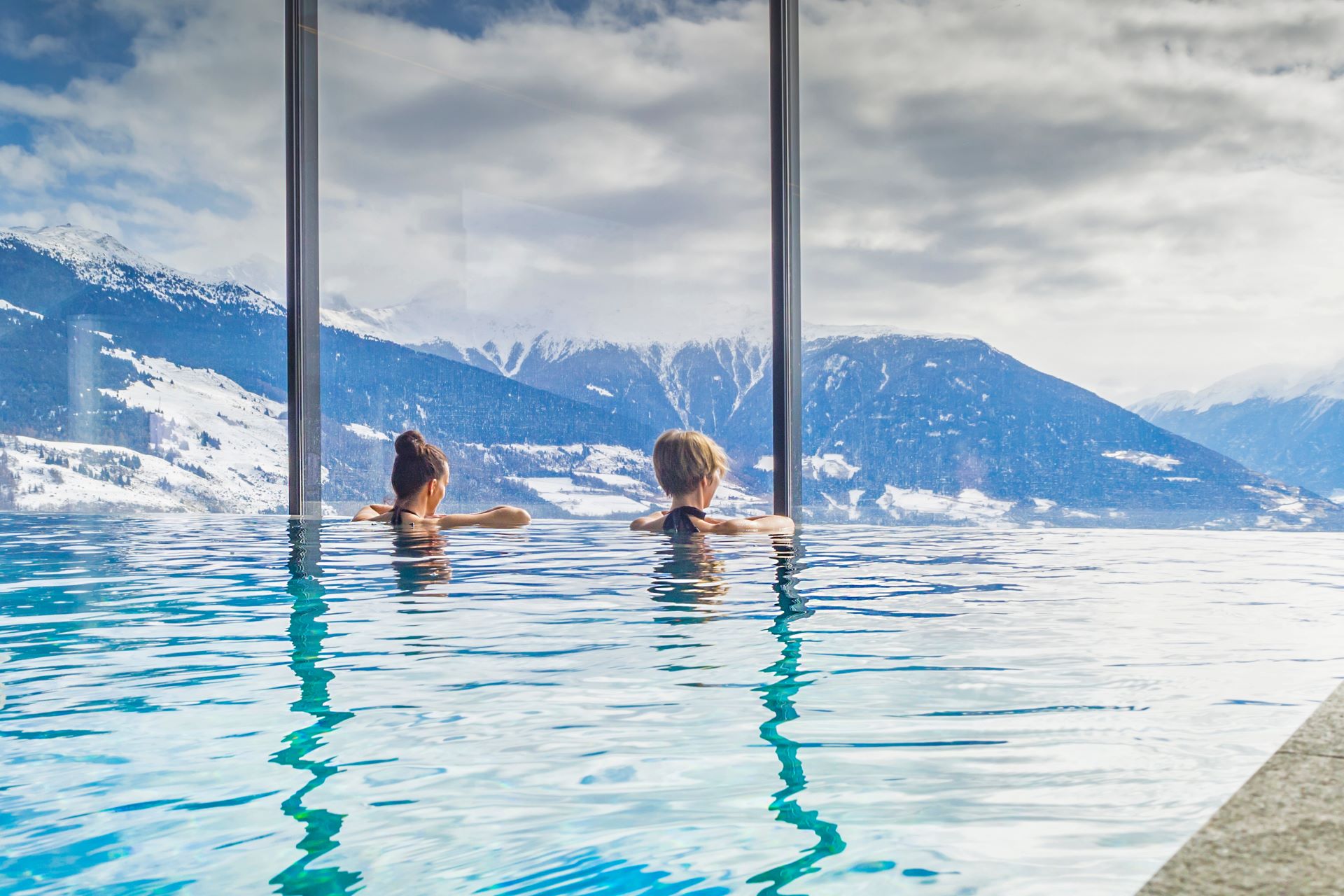 Zwei Frauen entspannen im Infinity-Pool mit Bergblick