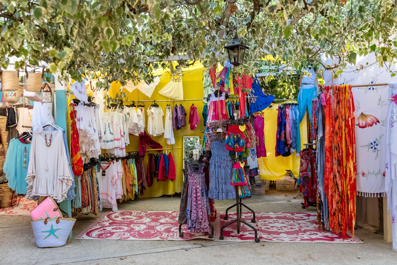 Bunter Stand auf dem Hippie-Markt Las Dalias auf Ibiza, voller Kleidung und Accessoires – ein Highlight neben jedem Ibiza Restaurant Geheimtipp.